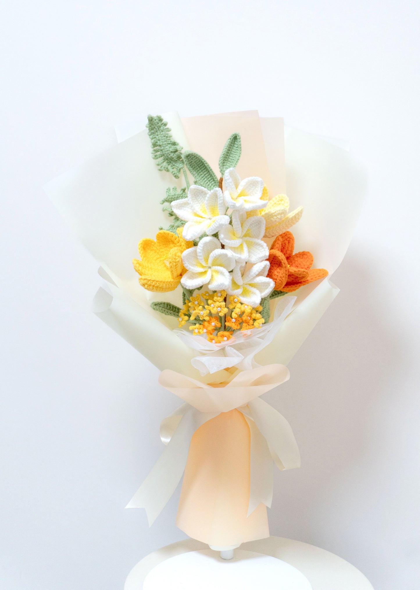 這款手工編織花束結合雞蛋花、鬱金香與滿天星花朵,採用白色、黃色與橙色等多色設計,搭配綠葉與薄紗包裝,綁上淡雅緞帶,展現溫暖治癒風格。適合作為康復祝願送給親友,或用於生日/節日表達關懷。花束永不凋謝,象徵長久祝福,附贈卡片增添個人化心意,是手工愛好者與送禮者的優選,體現獨特工藝與溫馨情感。